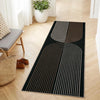 A long runner rug with black and beige geometric stripes on a light wood floor.