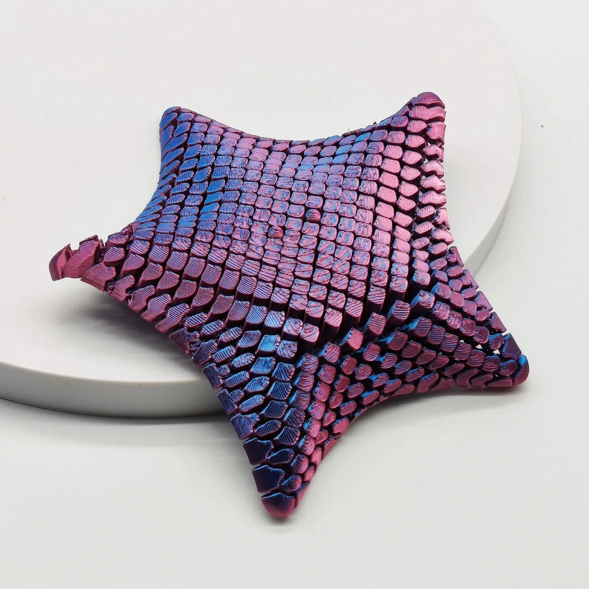 A purple and pink 3D printed starfish fidget toy with a textured, scale-like surface.
