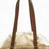 A close-up of a tan leather handle attached to a handwoven straw tote bag.
