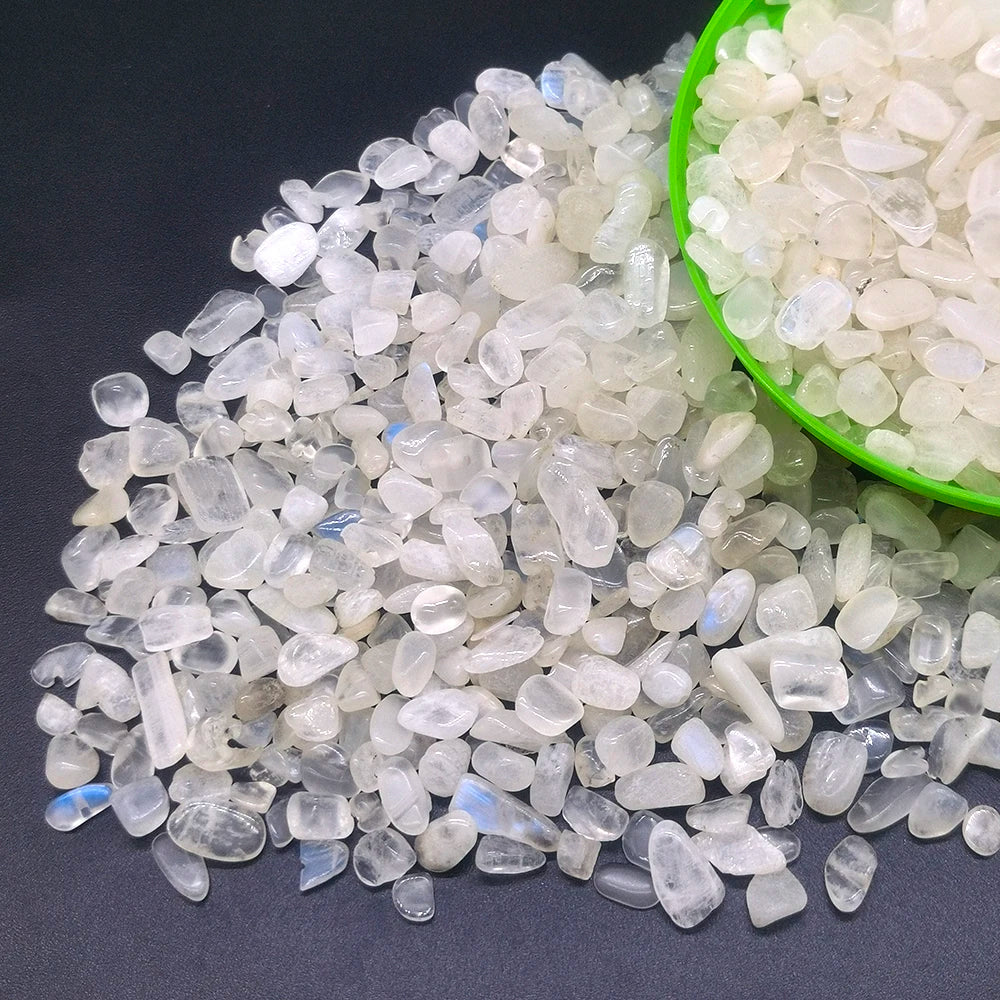 A pile of clear and translucent natural crystal stone chips in various sizes, some contained in a green bowl.