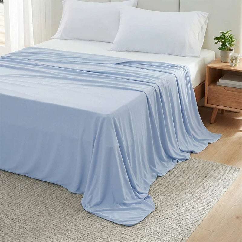 Light blue ice silk blanket draped over a bed and resting on a beige rug.