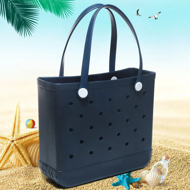 Dunkelblaue, portable EVA-Strandtasche auf goldenem Sand mit Seesternen und Muscheln.