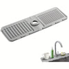 A gray silicone mat with ridges and a central opening used as a splash guard for kitchen or bathroom faucets.