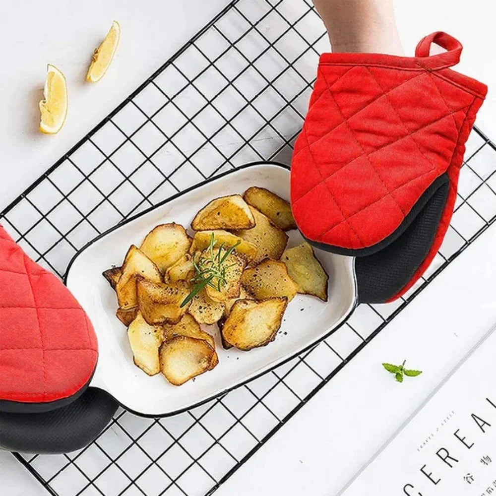 Red heat-resistant silicone oven mitts with black grips holding roasted potatoes on a white plate.