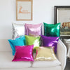 A collection of vibrant metallic pink, green, purple, and gold decorative pillowcases displayed on a white sofa.