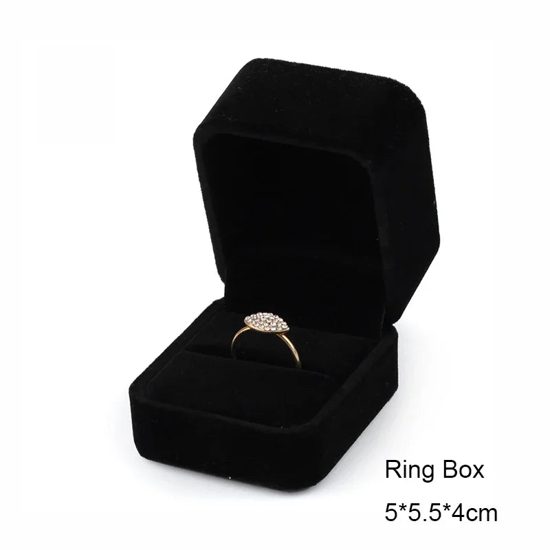 A black velvet ring box containing a gold-toned ring.