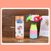 A DIY flower craft kit showing colorful felt buttons and flowers arranged in a glass vase.