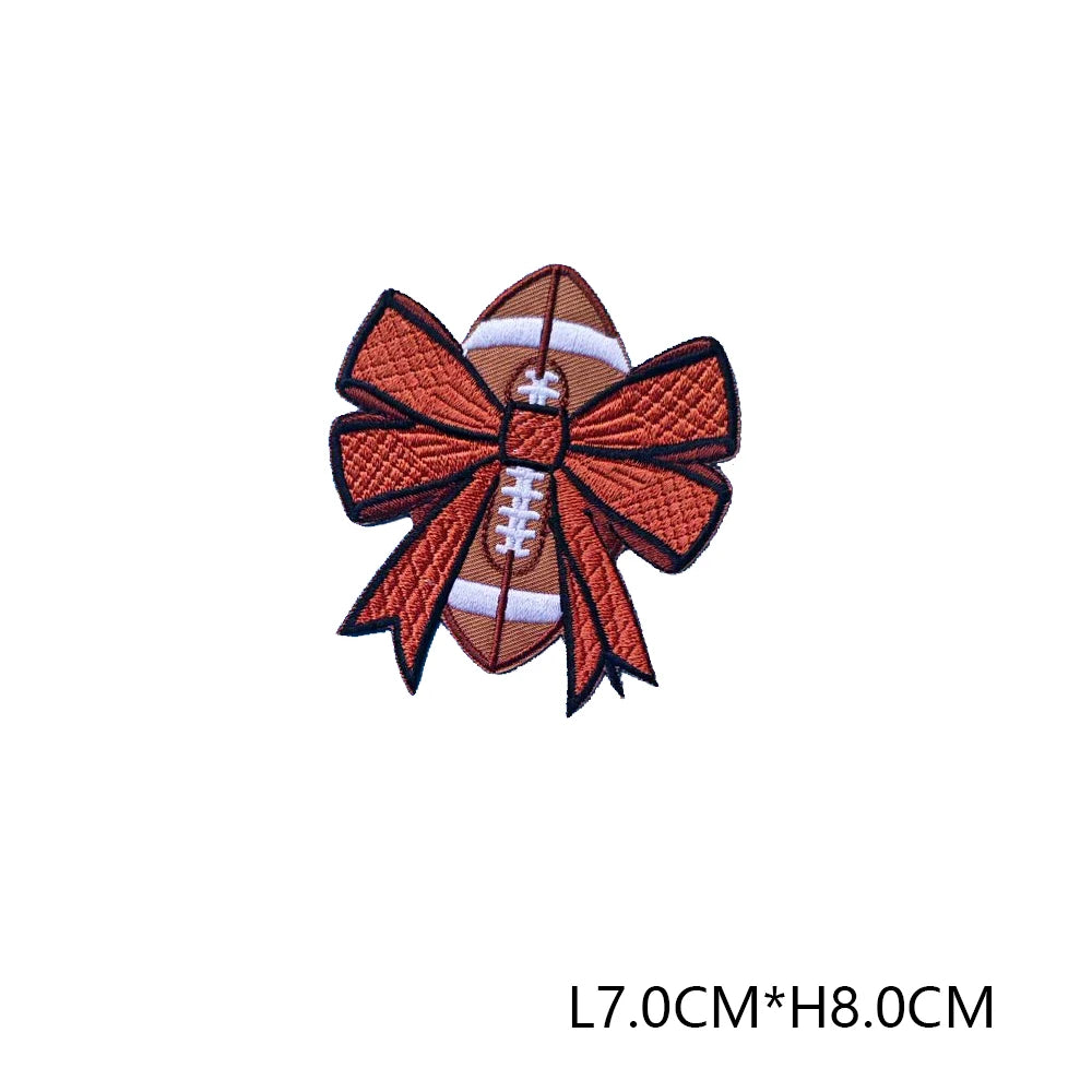 An embroidered letter patch in brown and white featuring a bow design.