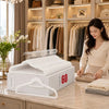 A woman is arranging white velvet non-slip hangers on a marble countertop in front of a wooden closet shelf.