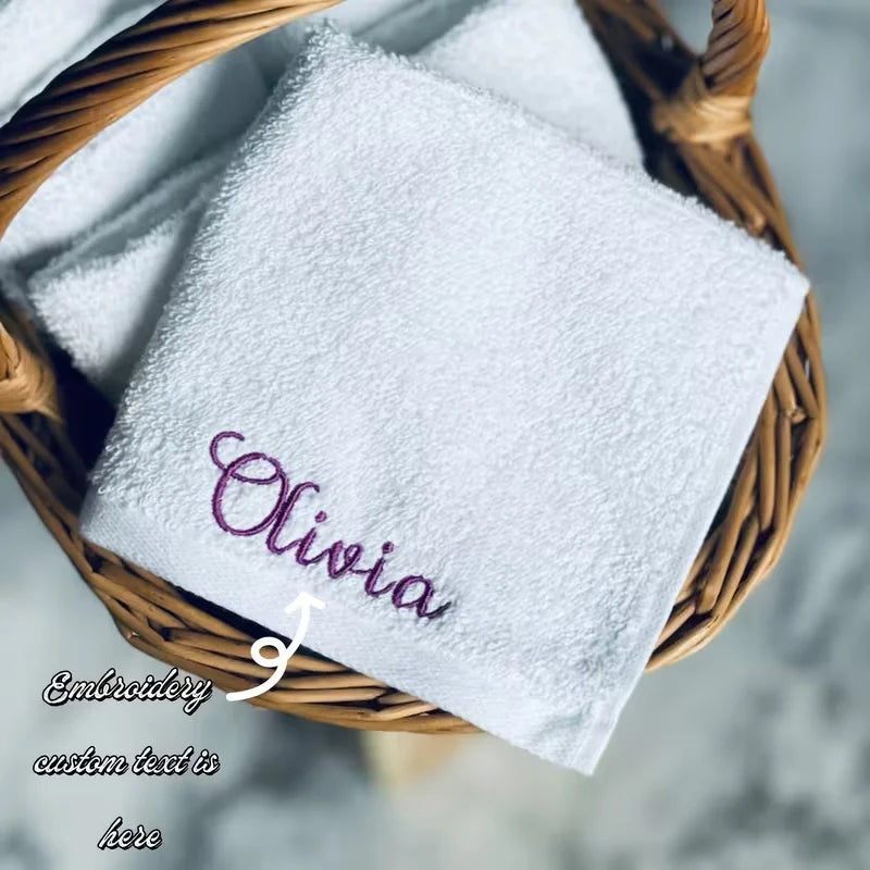 White embroidered face towel with the name Olivia in purple thread resting in a woven basket