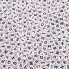 A close-up view of numerous white acrylic alphabet letter beads scattered on a surface.