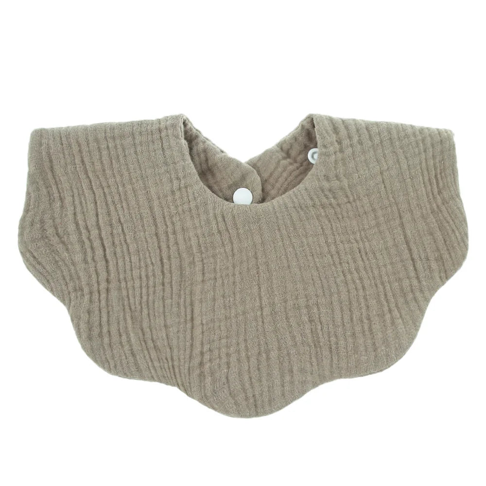 A beige knitted baby bib in a bandana style with a rounded neckline.