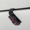 A black clip with purple and pink crystal rhinestones used to secure a car sun visor.