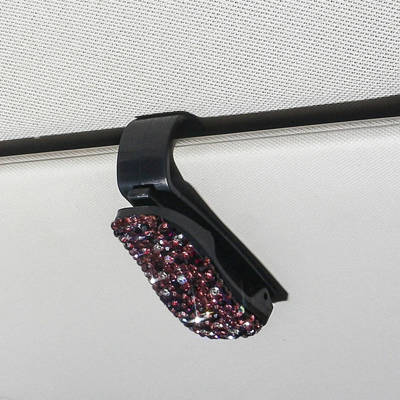 A black clip with purple and pink crystal rhinestones used to secure a car sun visor.
