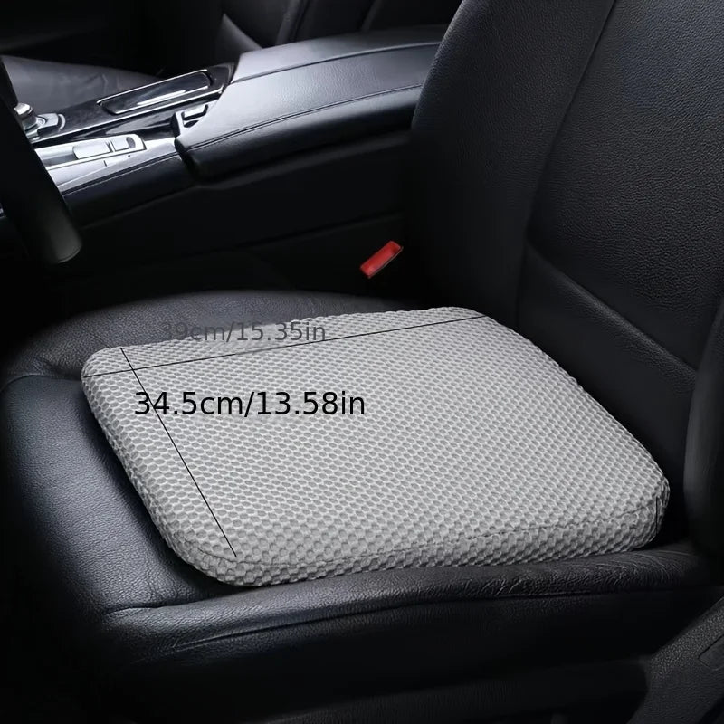 A gray height-increasing car seat cushion is shown placed on a black car seat.