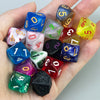 A hand holds a collection of ten polyhedral dice in various colors and shapes for tabletop role-playing games