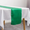 A vibrant green satin table runner draped on a white tablecloth for an elegant event setting.