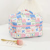 A pink and blue patchwork quilted makeup bag with a pleated lid rests on a white surface.