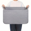 A gray woven cotton rope storage basket being held by a person.