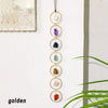 A vertical display of seven crystal pendants in various colors hanging on a white wall.