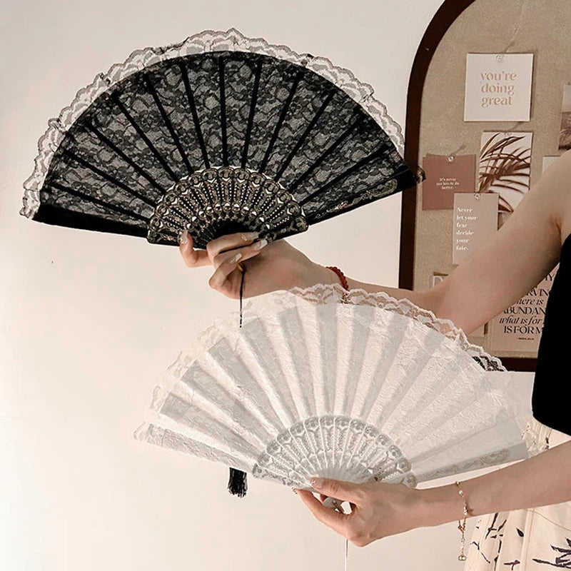 A person holds a vintage lace folding hand fan with a durable handle, displaying the intricate black and white patterned fan.