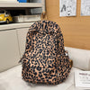 A brown and black leopard print nylon backpack with multiple pockets resting on a light-colored surface.