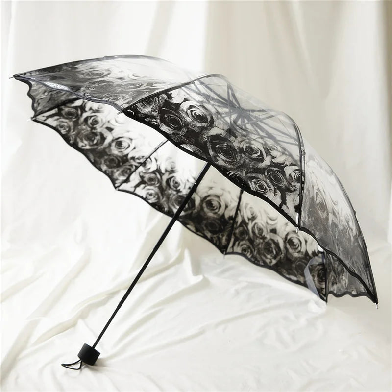 A black umbrella with a transparent canopy featuring a floral design, shown open against a white background.