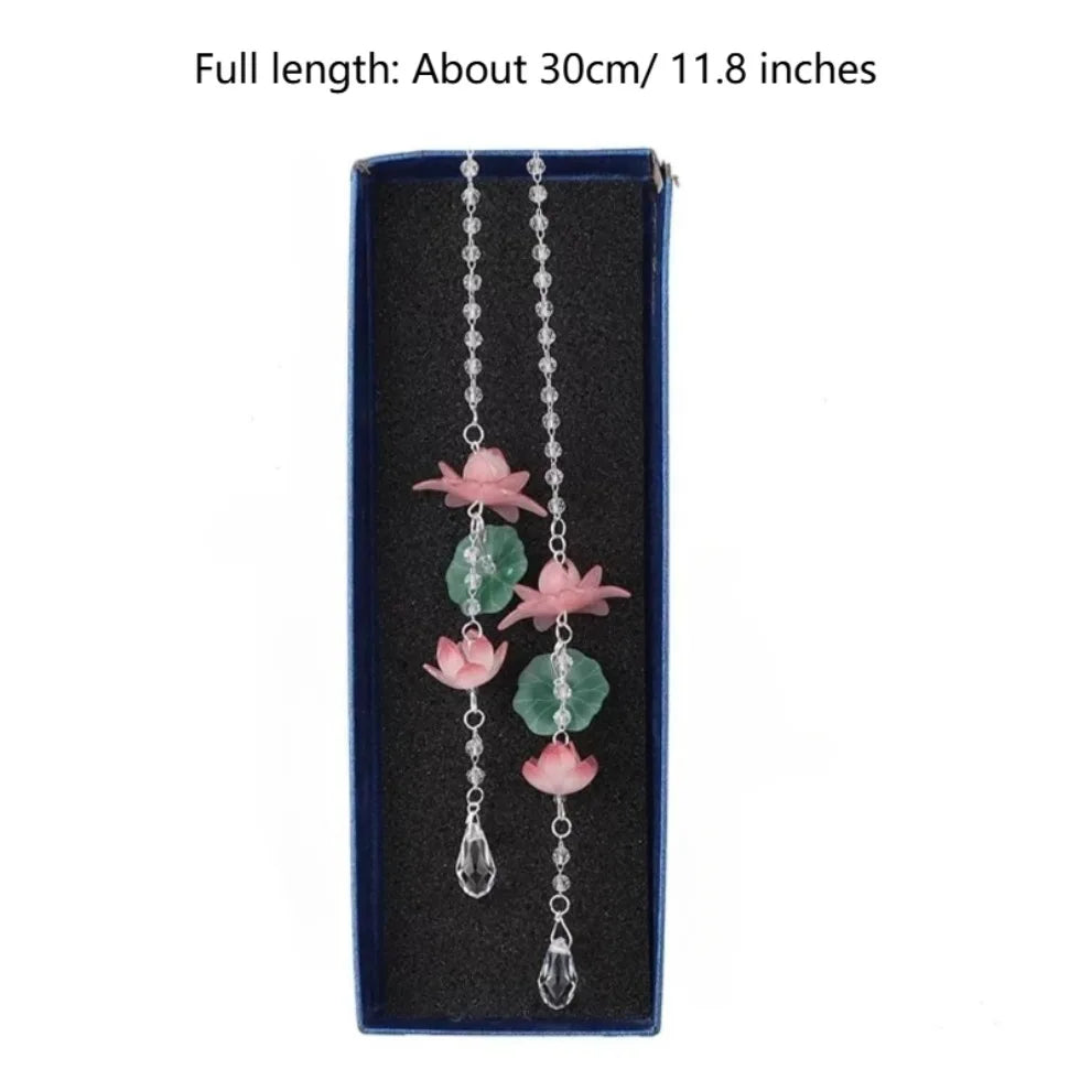 A silver chain necklace featuring pink lotus-shaped pendants on a dark blue background.