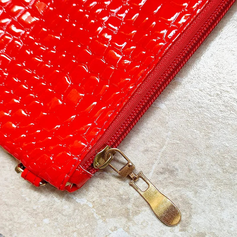 Close-up of a red crocodile embossed fabric bag with a gold metal zipper pull replacement slider.