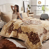 A beige weighted plush blanket is displayed on a bed, with a woman sitting beside it in a bright bedroom setting.
