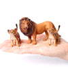 A realistic brown lion figurine is shown next to several small, detailed animal figurines held in a person's hand.