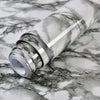 Roll of marble contact paper with gray and white veining lying on a marbled surface