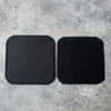 Two black embroidered tactical patches with hook and loop backing placed on a gray textured surface.