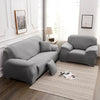 A modern gray stretchable sofa cover is displayed in a bright room with natural light.
