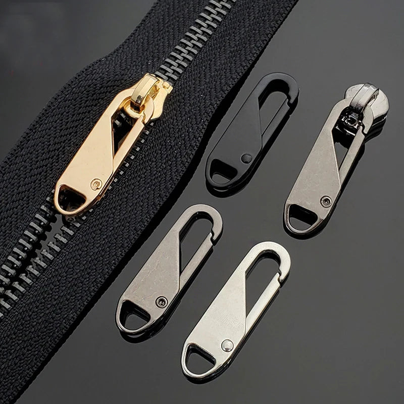A close-up view of a black zipper with various metal slider components, including a brass zipper pull and several silver meta