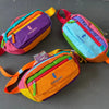 A collection of colorful waterproof nylon fanny packs in various color blocks, including purple, orange, pink, and teal.