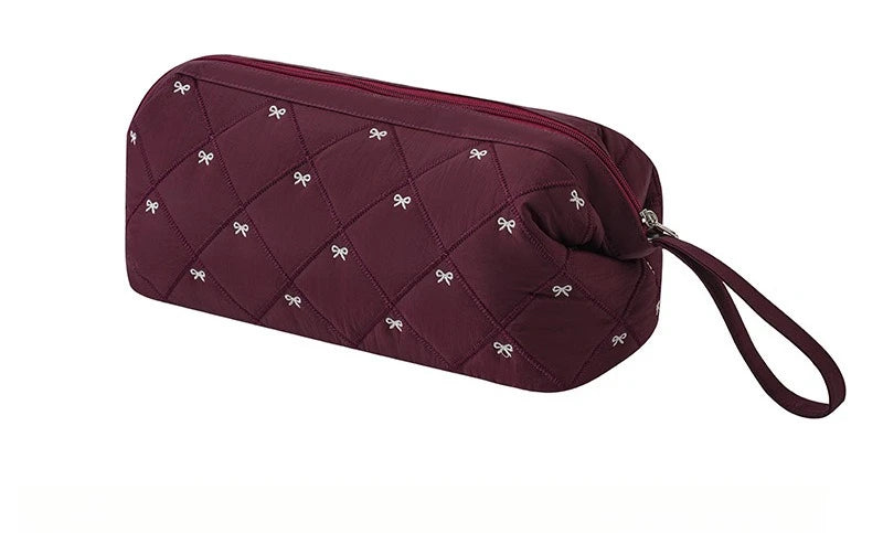 A maroon quilted storage bag for a portable hair dryer and styling tool.