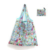 A light blue reusable shopping tote bag featuring a floral pattern and an attached carry pouch.
