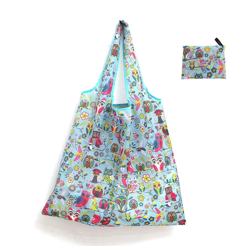 A light blue reusable shopping tote bag featuring a floral pattern and an attached carry pouch.