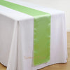 Elegant satin table runner in lime green draped across a white tablecloth.