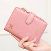 A pink leather passport wallet with an airplane pattern and RFID protection is being held by a hand.