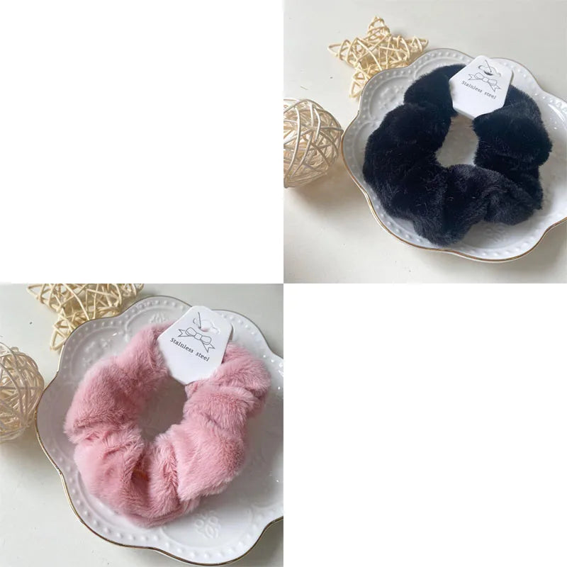 A close-up of a black plush coil hair tie and a pink plush coil hair tie displayed on white plates.