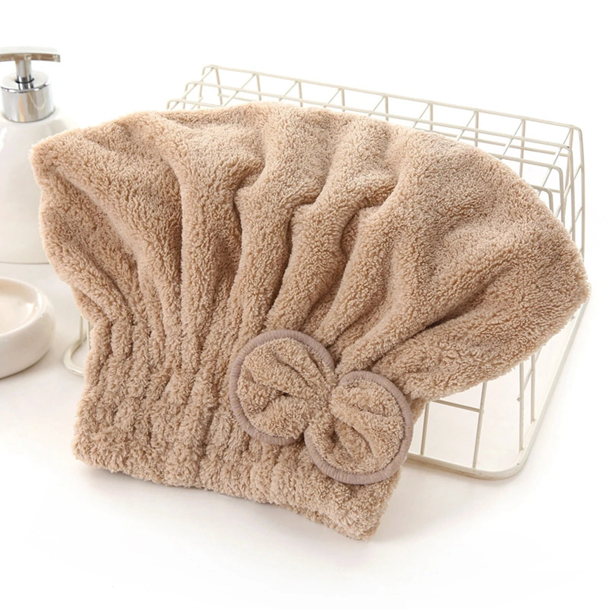 A beige microfiber hair drying towel with a bow-knot head wrap is displayed on a wire rack.