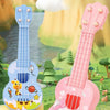 A pink mini ukulele toy guitar with a cute cartoon cat design is displayed outdoors on a grassy area.