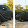 A black all-weather car cover is shown covering an SUV and a sedan outdoors.