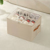 A beige foldable shoe organizer with a clear lid is shown resting on a light-colored textured surface.