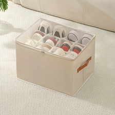 A beige foldable shoe organizer with a clear lid is shown resting on a light-colored textured surface.