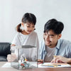 Un homme et une fille regardent une tirelire en acrylique sur une table avec des papiers.