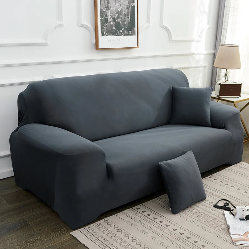 A dark gray silky soft stretchable sofa cover for pet owners displayed on a light rug.