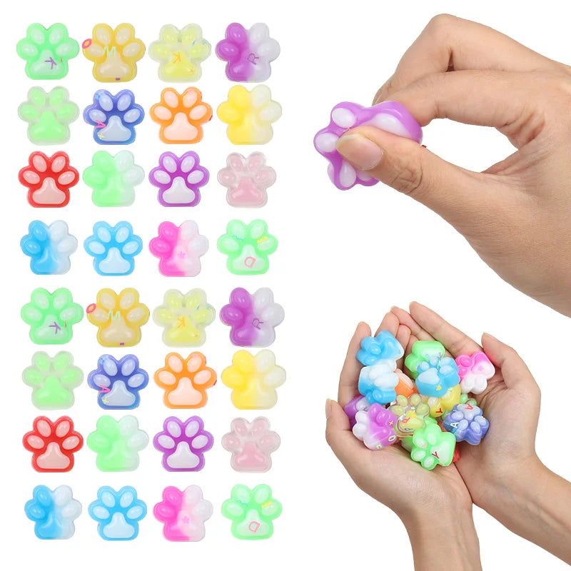 A hand holds various colorful squishy cat paw fidget toys for stress relief and sensory play.
